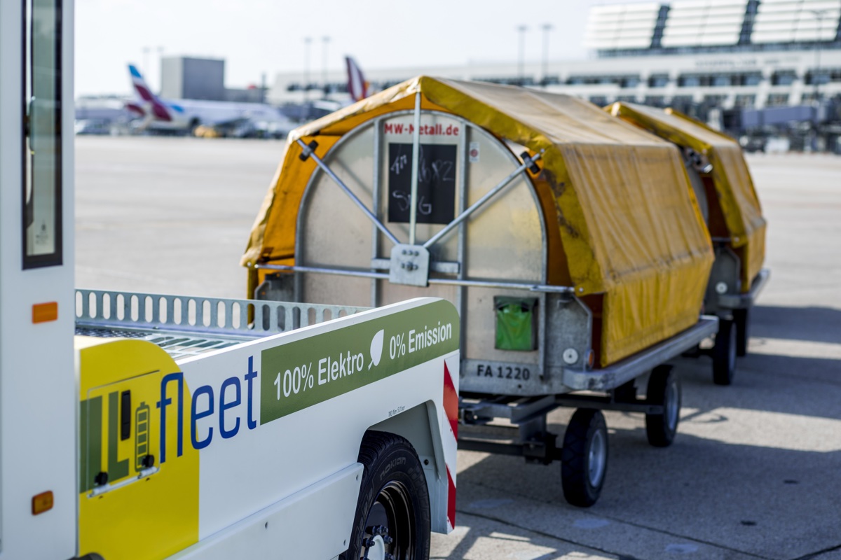 Elektrischer Gepäckschlepper transportiert Gepäckanhänger auf dem Vorfeld