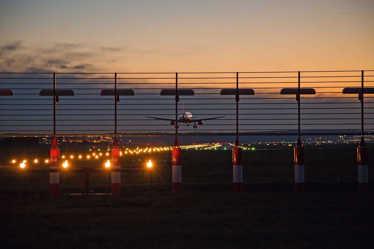 Flugzeug landet in der Abenddämmerung bei eingeschalteter Beleuchtung der Landebahn