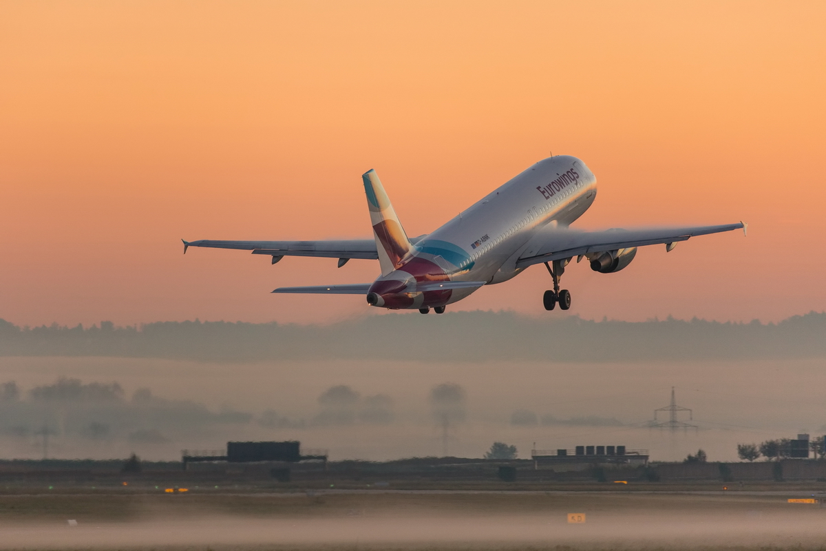 Flugzeug hebt in die Morgensonne bei Nebel ab