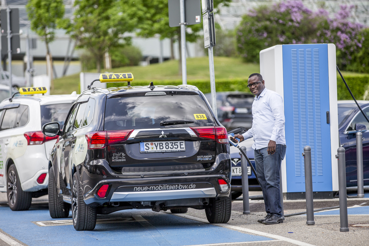 Taxifahrer lädt Fahrzeug an der Ladesäule auf