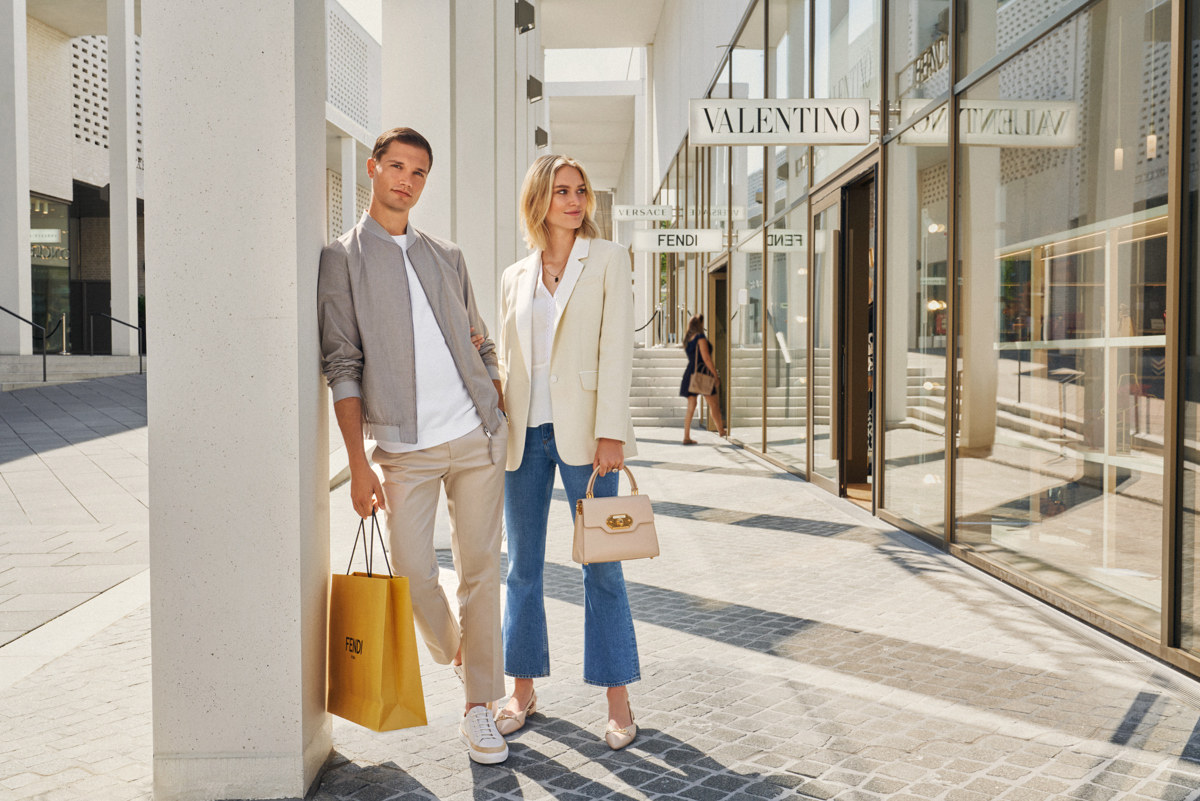 Ein Pärchen mit Einkaufstaschen steht in einer Einkaufspassage der Outletcity Metzingen