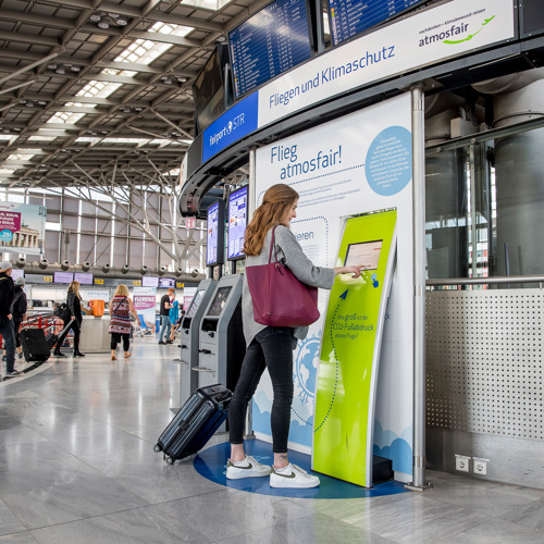 Eine Passagierin berechnet die Emissionen ihres Fluges an der Atmosfair Station im Terminal.