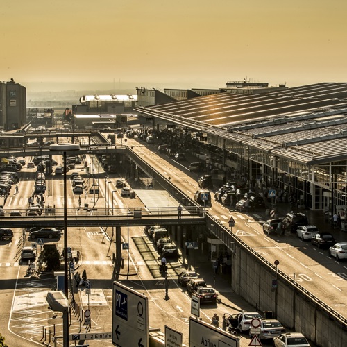 Terminalvorfahrten und Parkplätze neben den Gebäuden im Sonnenlicht mit vielen Autos