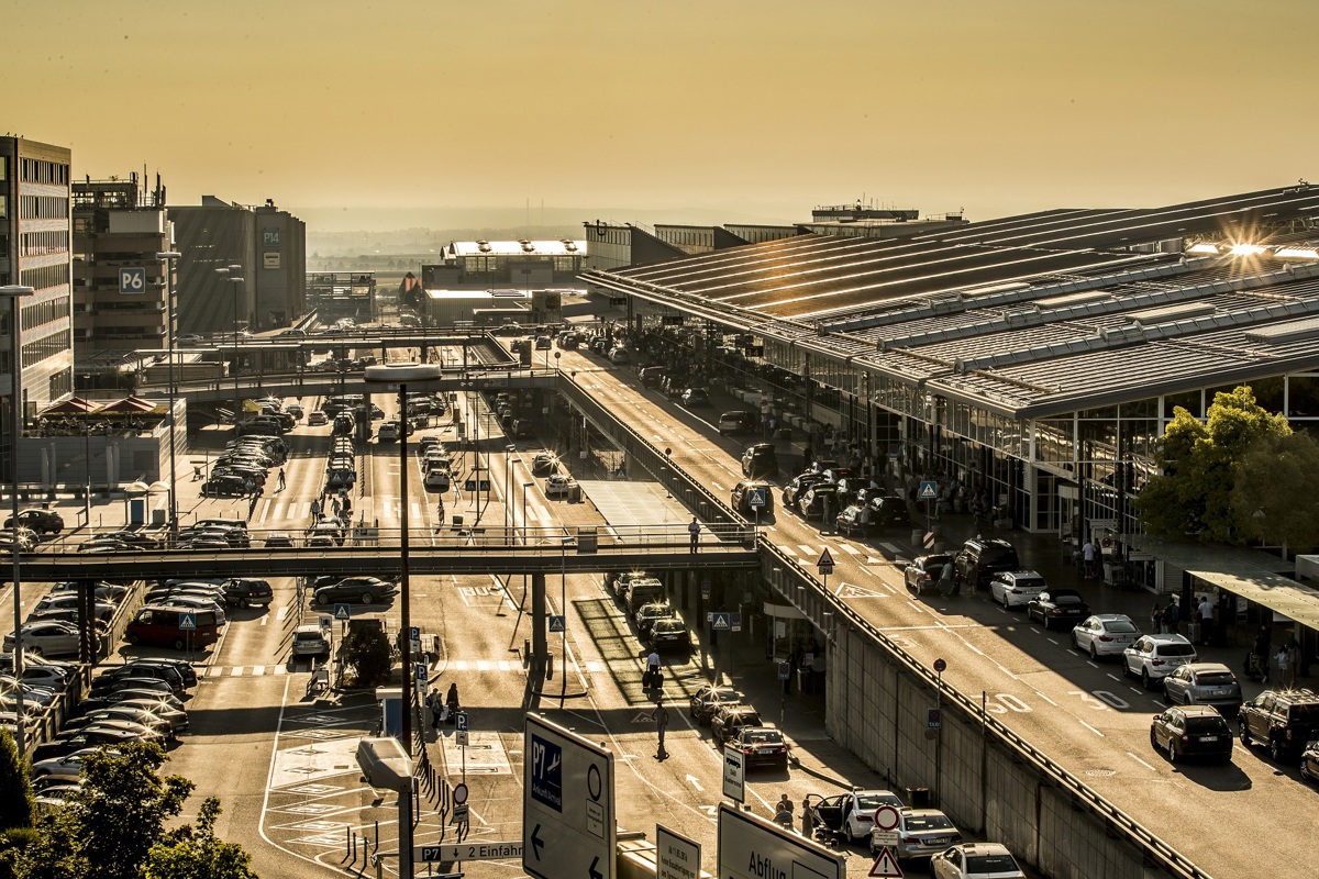 Terminalvorfahrten und Parkplätze neben den Gebäuden im Sonnenlicht mit vielen Autos