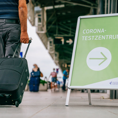 Schild mit Wegweiser zum Coronatestzentrum vor dem Terminal