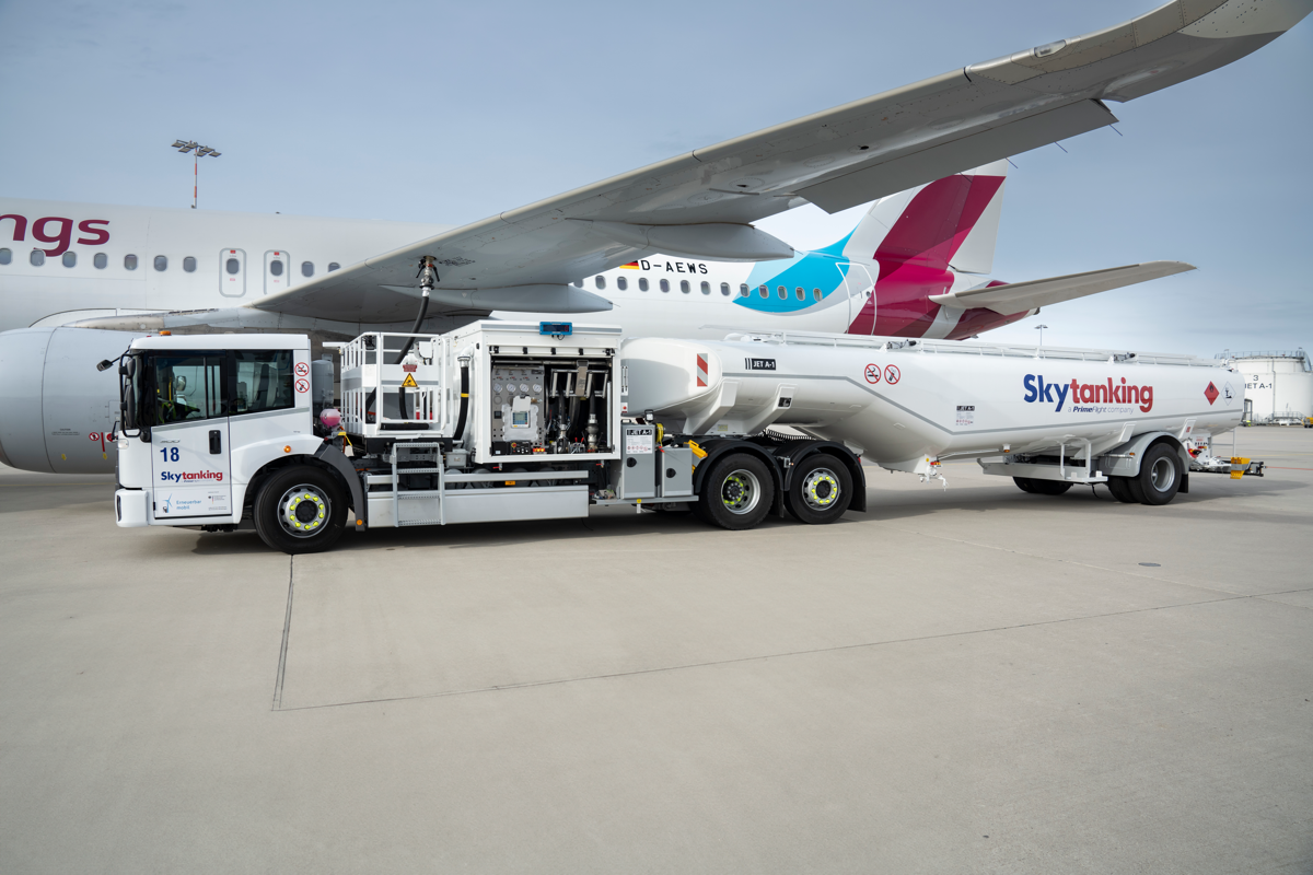 Ein elektrischer Flugzeugtankwagen der Firma Skytanking betankt ein parkendes Flugzeug.